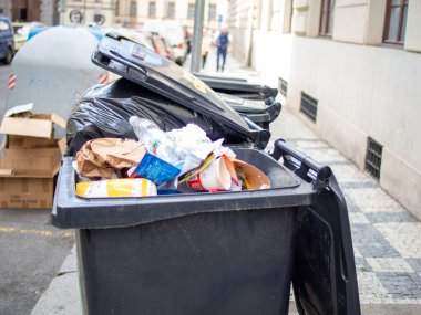 Çöplerle dolu bir çöp tenekesi çöp kamyonu tarafından toplanmayı bekliyor..