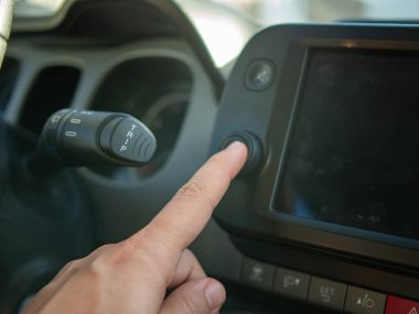 Modern bir araba multimedya dokunmatik ekran konsolundaki başlat düğmesine basan parmağın yakın plan görüntüsü