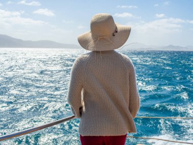 Şapka takan ve okyanusta yelken açan bir kadın.