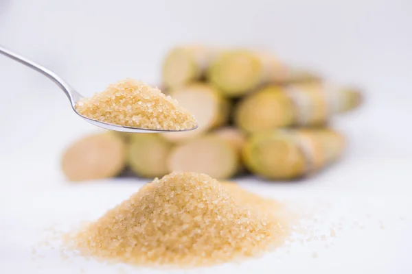 Kahverengi şekeri kaşık içinde şeker kamışının arka planında kapat