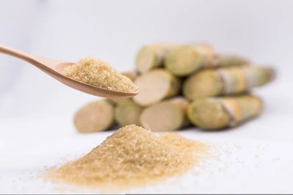 Kahverengi şekeri kaşık içinde şeker kamışının arka planında kapat