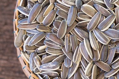 Tahta arka planda bambu sepetinde ayçiçeği çekirdeği yığını