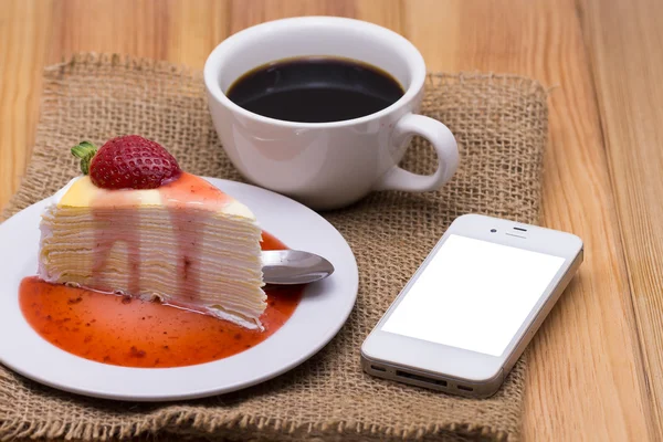 coffee cup, smart phone and cakes on wood background.