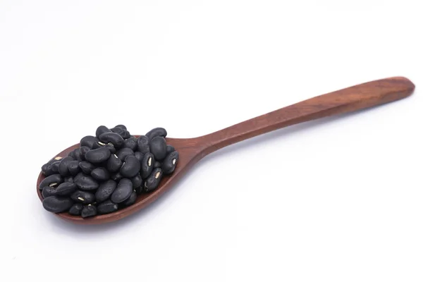Frijoles negros en cuchara de madera aislados sobre fondo blanco — Foto de Stock