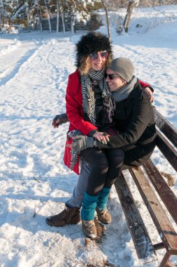 Young couple sitting on a bench in a park in Winter