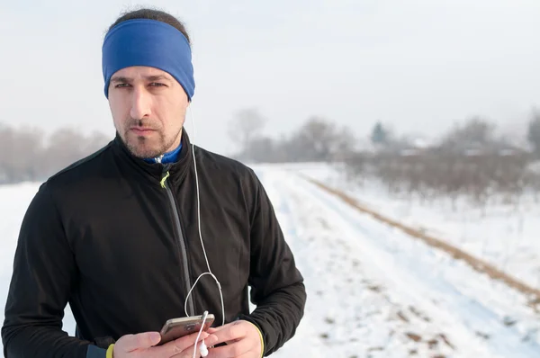 Mannelijke atleet luisteren muziek van smartphone op de winterdag — Stockfoto