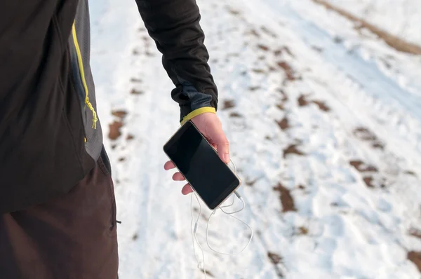 Loper met smartphone. Winter, buiten, sneeuw — Stockfoto