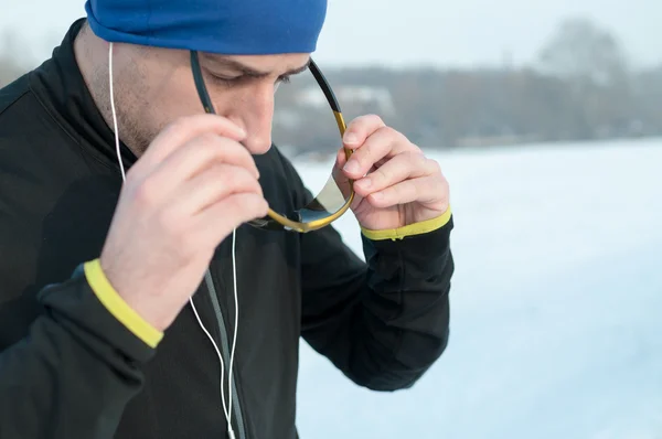 Homem coloca esporte glasess antes de correr na neve — Fotografia de Stock