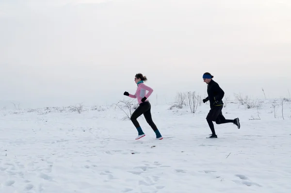 Homme et femme courant sur la neige — Photo