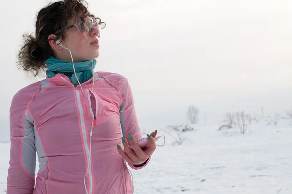 Girl runner listen music from smartphone on winter day — Stock Photo, Image