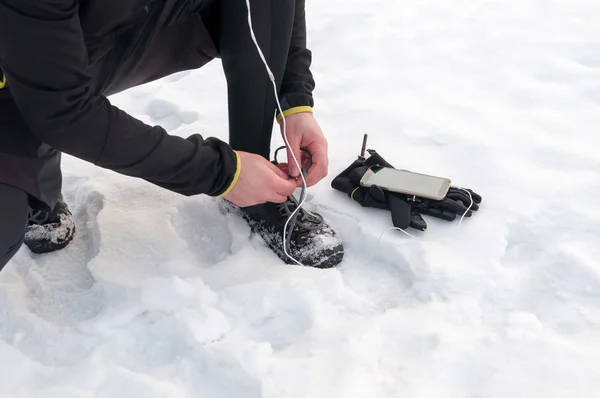 Homem amarrando tênis de corrida na neve — Fotografia de Stock