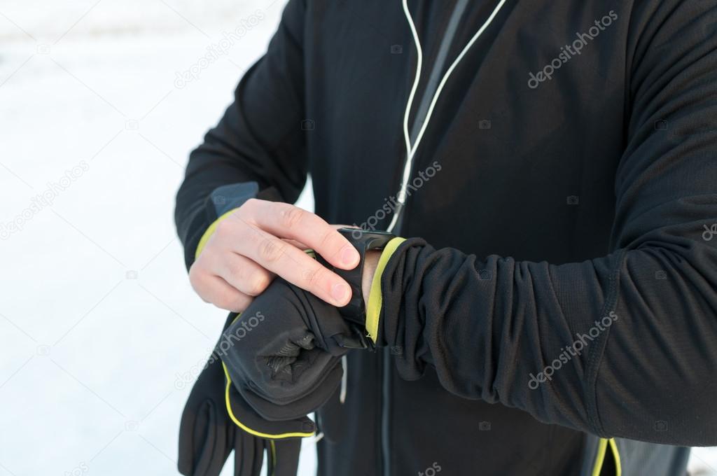 Runner using smartwatch. Outside, snow, winter
