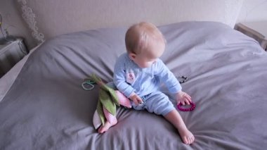 Bir bebek oturma ve brecelets ile oynarken bir yatakta