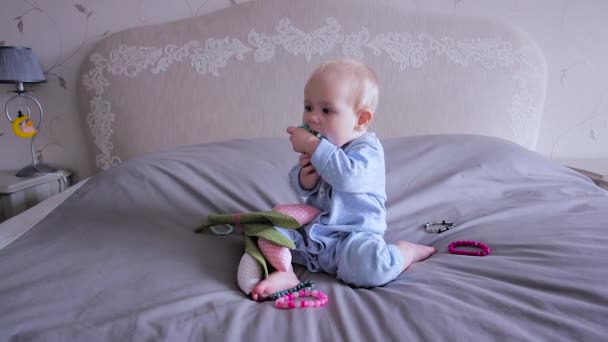 Un bebé en una cama sentado y jugando con panecillos — Vídeos de Stock