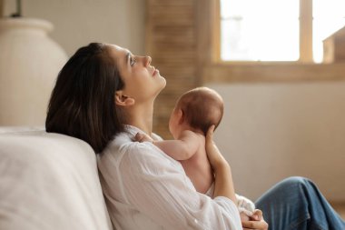 Büyüme ve diş çıkarma kavramı. Yorgun bir anne yerde oturuyor ve kucağında küçük bir bebek var. Doğum sonrası depresyondan muzdarip.