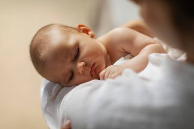 Anne güzel uyuyan bebeğini elinde tutuyor, ninni söylüyor, tatlı bebeğe odaklanıyor, yakın plan çekiyor.