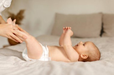 Bakıcı anne, yeni doğmuş bebeğine masaj yapıyor ve jimnastik yapıyor. Küçük çocukla egzersiz yapıyor.