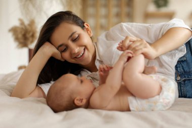 Sevecen anne bağlanıyor ve küçük kızına bakıyor. Sevgiyle ve nazikçe bacaklarına dokunuyor. Evde yatakta yatıyor.