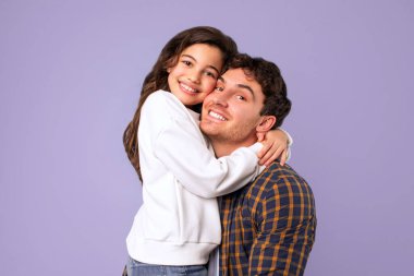 Babalığın neşesi. Sevgi dolu baba kızını kucaklıyor, ilgi ve sevgisini ifade ediyor, mor stüdyo geçmişi var. Aile mutluluğu, tatlı anlar