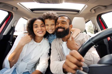 Üç kişilik heyecanlı Latin ailesi arabada oturuyor ve poz veriyor. Oğul, anne babayı arkadan kucaklıyor, tatilin tadını çıkarıyor, kameraya otomatik olarak gülümsüyor.