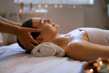 Rahatlamış genç bir kadının Tayland kaplıcasında yüz masajı yaptırdığı ve modern kaplıcada akupunktur masajının keyfini çıkardığı profil fotoğrafı. Yüz gerdirme, yaşlanma karşıtı konsept