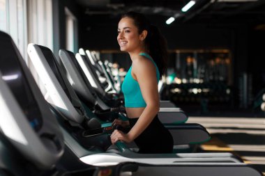 Sportif bir kadının koşu bandında sıkı kardiyo çalışması, boş bir salonda koşması, kardiyo çalışması. Spor anlayışı, vücut geliştirme