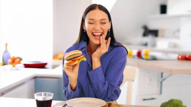 Oburluk. Tatmin olmuş bir bayan hamburger yemeyi sever. Evdeki mutfakta oturup fotokopi çekmeyi sever. Sağlıksız beslenme ve aldatma yemek konsepti