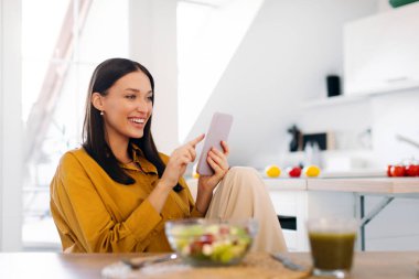 Mutfakta cep telefonuyla konuşan bir bayanın taze sebze salatasıyla masada oturmasına sevindim. Diyet uygulaması, kilo verme günlüğü