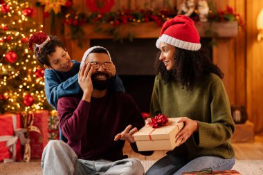 Afrika kökenli Amerikalı çocuk, babasının gözlerini kapatıyor. Anne, Noel 'i evde kutlayan üç kişilik aile Xmas için hediye paketi hazırlıyor.