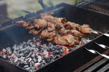 Sıcak kömürlerin üzerinde et ızgara, arka bahçede piknik et dumanı yükselirken et pişerken