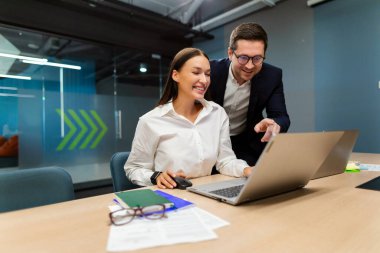 Happy lady assistant and her male boss working together, using laptop in office, coworkers preparing business project, brainstorming for startup ideas