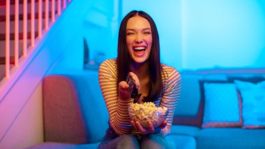 Aşırı mutlu Avrupalı kadın elinde uzaktan kumanda, kanal değiştirme, film gecesi koltukta oturma, panorama