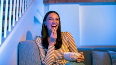 Film gecesi. Mutlu bayan komik komedi filmi izliyor, patlamış mısır yiyor, evdeki koltukta oturuyor, panorama, boş yer. Dijital eğlence ve eğlence eğlencesi