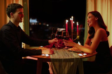 Sevgililer Günü 'nü kutlayan aşıklar, romantik bir akşam yemeğinde şarap bardakları tokuşturan aşıklar.