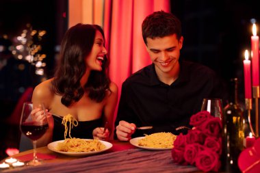 Sevgililer Günü 'nü romantik bir ortamda kutlarken restoranda randevuya çıkan, gülen, yemek yiyen, şarap içen çiftler.