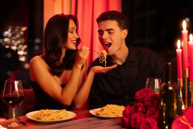 Lokantada romantik bir akşam yemeği yerken birbirini besleyen çift lezzetli makarna yiyor, Sevgililer Günü 'nü kutluyor.