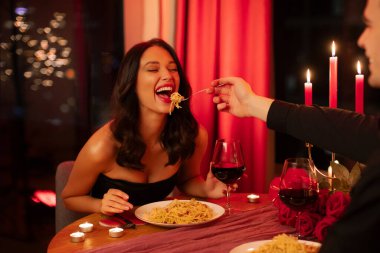 Aşk ritüelleri. Mumlarla romantik bir akşam yemeği, spagettiyle beslenen bir adam, özel bir ortamda sevgililer gününü kutlayan bir çift.