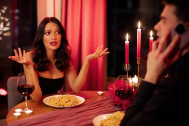 Lokantada romantik bir akşam yemeği sırasında cep telefonundan erkek arkadaşına bakan kızgın bir kadın. Sevgililer gününde randevusu olan bir çift.