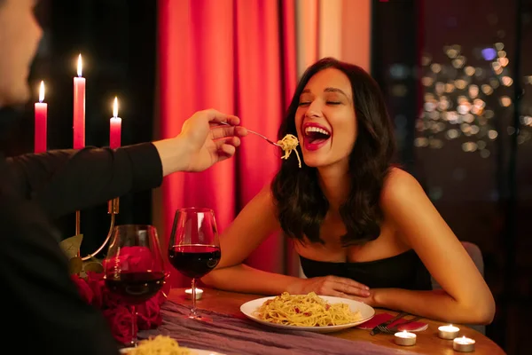 Akşam yemeğinde makarna yiyen bir adam, romantik bir çift, kırmızı mumlar ve şarap bardakları masada, Sevgililer Günü kutlamaları...