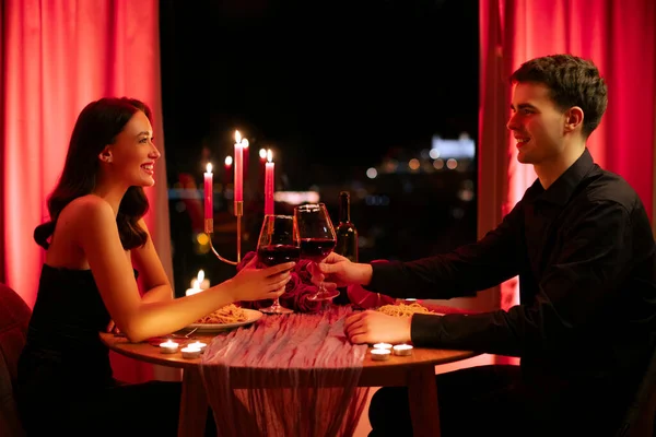 Sevgililer Günü. Aşıklar romantik bir buluşmada şarap bardaklarını tokuşturur, akşam restoranda tatil kutlar, kenar manzaralı...