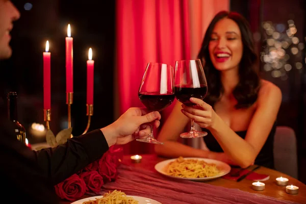 Romantik, loş bir ortamda akşam yemeğinin tadını çıkaran çift akşam Sevgililer Günü 'nü kutlarken şarap içiyor.