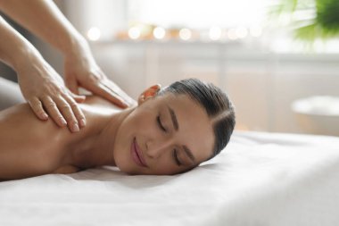 Rahatlıkla gülümseyen genç bir kadın sırt masajı alırken gündüzleri sıcacık bir ortam ve boş bir alan yaratıyor.