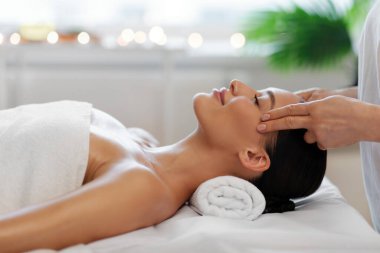 Dikkatli bir dokunuş. Mutlu bayan stres önleyici kafa masajı alıyor, rahat, lüks bir spa salonunda dinleniyor, yan görüş.