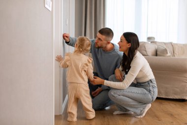 Genç ebeveynler, evde küçük bir kızın boyunu ölçüyorlar ve duvarda iz bırakıyorlar. Çocuk büyütme ve geliştirme kavramı