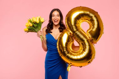 Bir buket sarı lale çiçeği ve 8 numaralı balon taşıyan heyecanlı genç kadın bahar tatilini kutluyor.