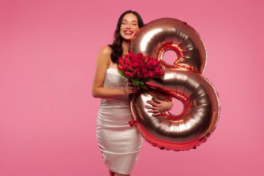 Laleli ve balonlu çekici Avrupalı kadın pembe stüdyo arka planında Kadın Günü 'nü kutluyor. 8 Mart tatili