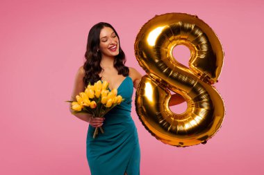 Mutlu Kadın Günleri. Zarif Avrupalı kadın elinde bir buket lale ve 8 numaralı balon ile pembe arka planda poz veriyor.