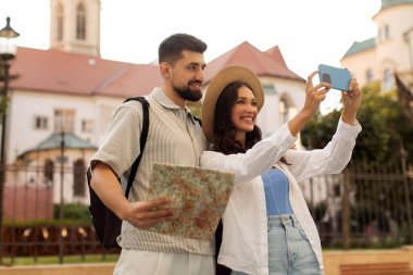 Şehirdeki tarihi binaların yakınında elinde harita tutan bir çift selfie ya da kadın çekiyordu.