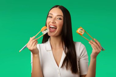 Yemek çubuklarıyla suşi yiyen mutlu bir kadın. Asya yemeği yemek gibi. Restoran ve yemek teslimatı gibi.