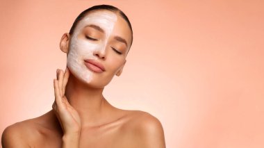 Organik kozmetik ürünü. Genç Avrupalı temizlikçi kadın, maske takıyor, sağlıklı şımartma tedavisinden hoşlanıyor, pembe stüdyo geçmişi var.